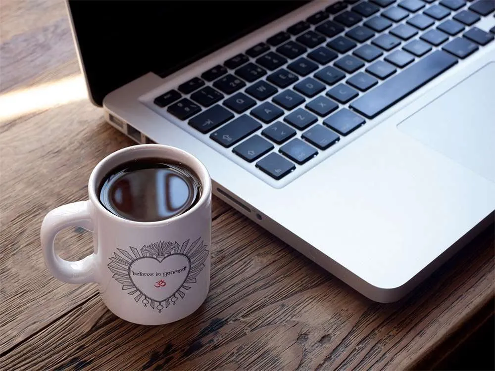 taza love yourself en mesa con macbook